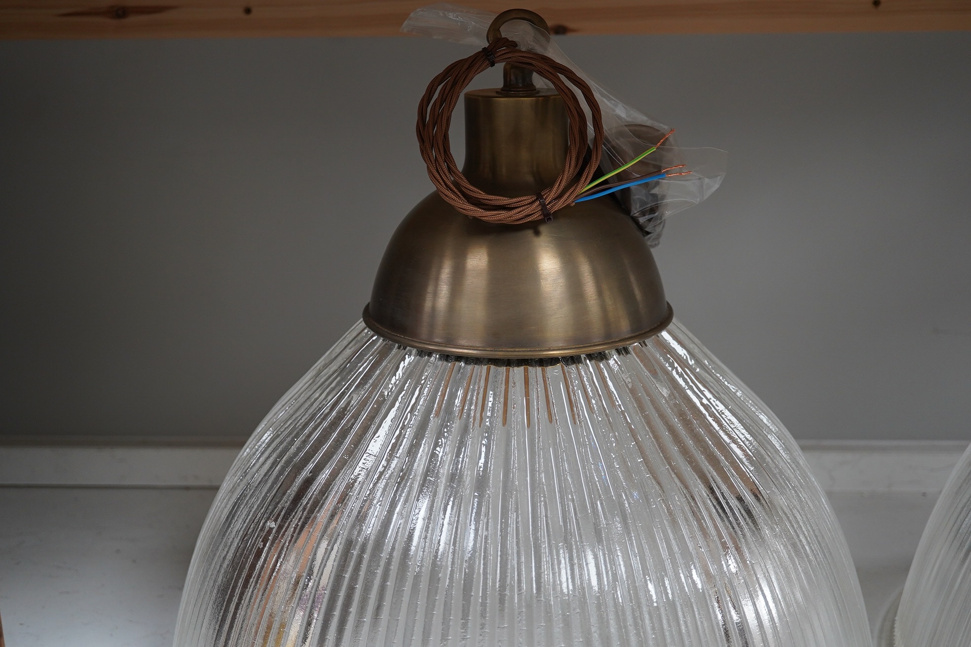 A large holophane pendant with antique brass gallery, chain and ceiling rose, wired, overall 44cm high to top of gallery, glass 47cm diameter. Condition - good